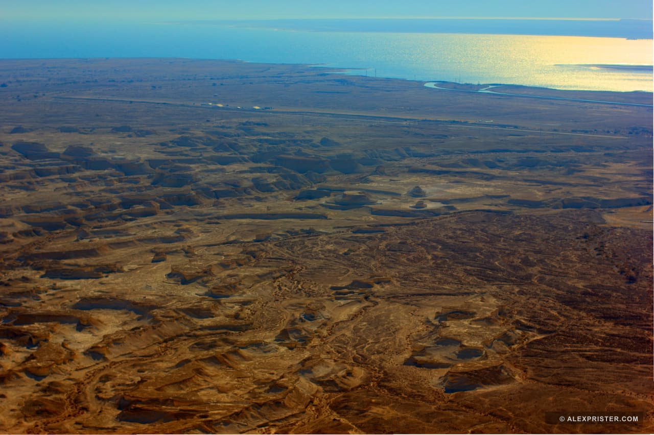 Aerial view of dry channels and layered brown desert terrain