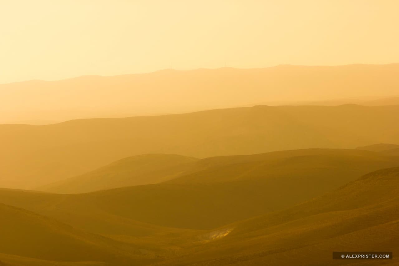 Successive mountain ridges fading into warm golden haze