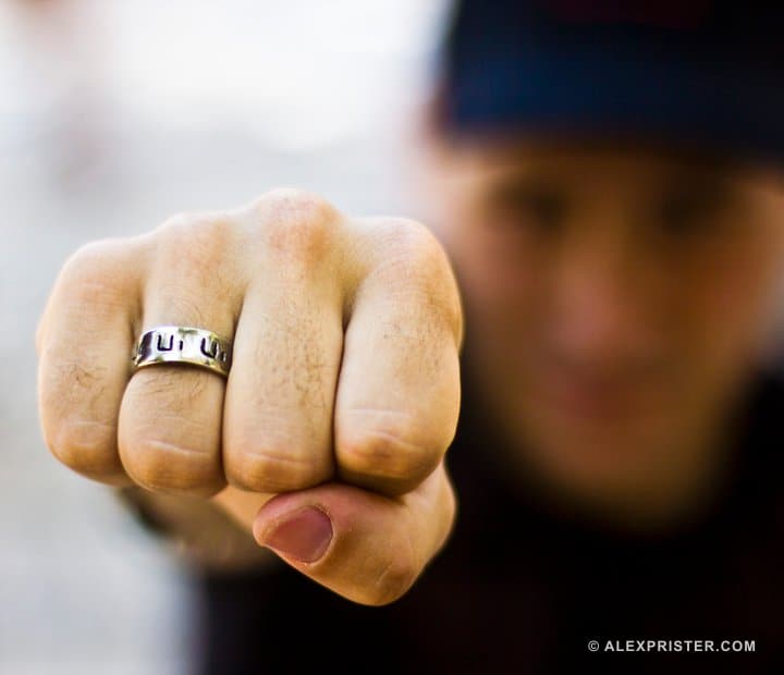 Close portrait focused on a ringed fist with a softly blurred person behind it